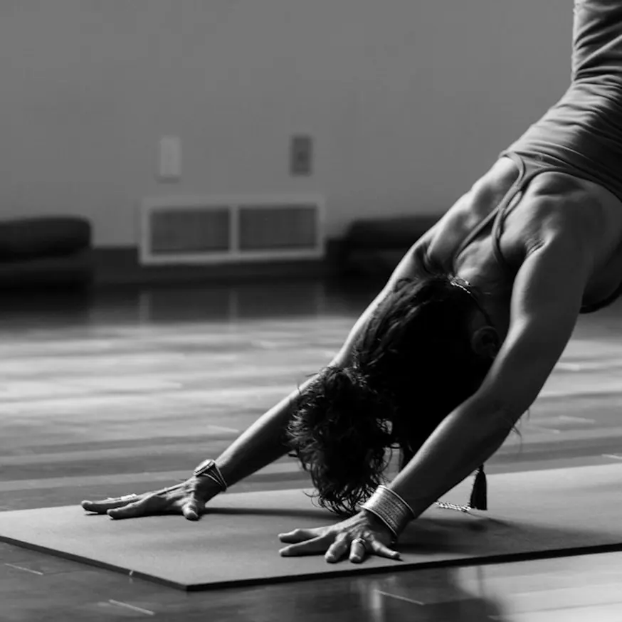 Black and white photo of a woman in a downward dog pose on a yoga mat