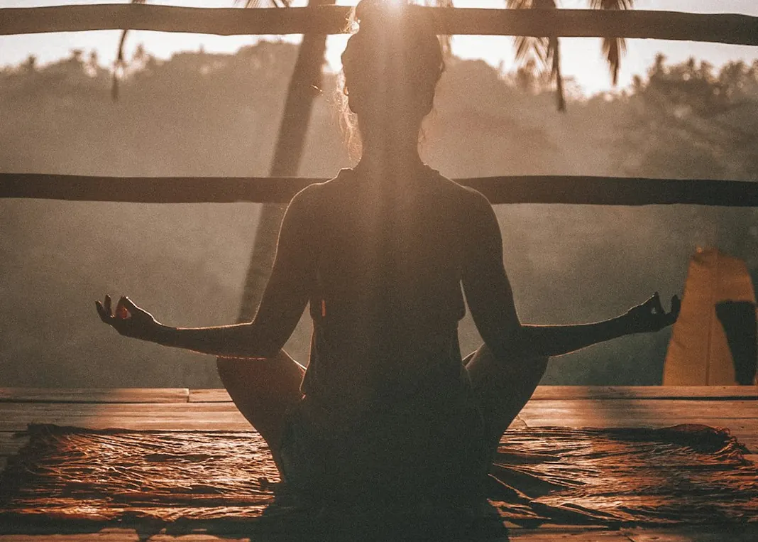 Silhouette of a person sitting in a meditation pose in warm evening light